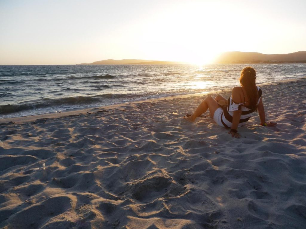 chica en playa observando el atardecer