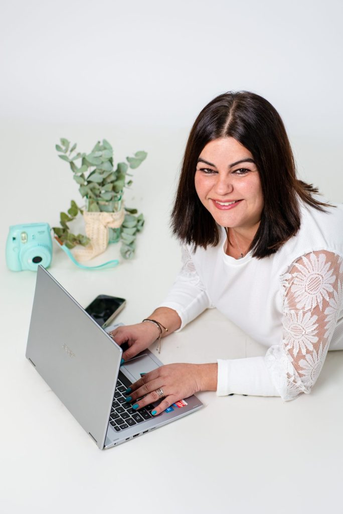 chica tumbada con portátil en el suelo mirando a la cámara